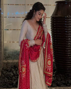 Cream designer gown with red bandhani dupatta – perfect wedding and festive outfit
